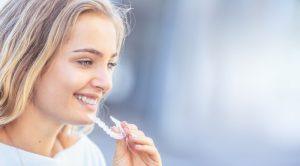young smiling woman holding Invisalign tray 