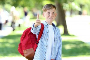 young boy with braces wearing red backpack