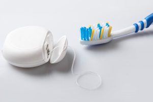 picture of toothbrush and floss next to one another 