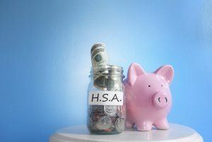 piggy bank sitting next to jar with “HSA” on it 