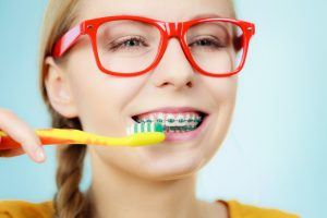 young woman with braces brushing 