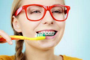 young woman with braces brushing