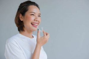 smiling woman about to put in Invisalign tray 