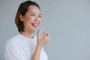 smiling woman about to put in Invisalign tray